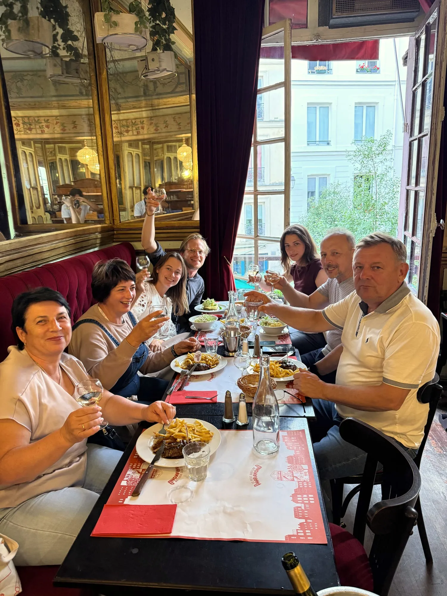 A group of guests toast with white wine at a long bistro table