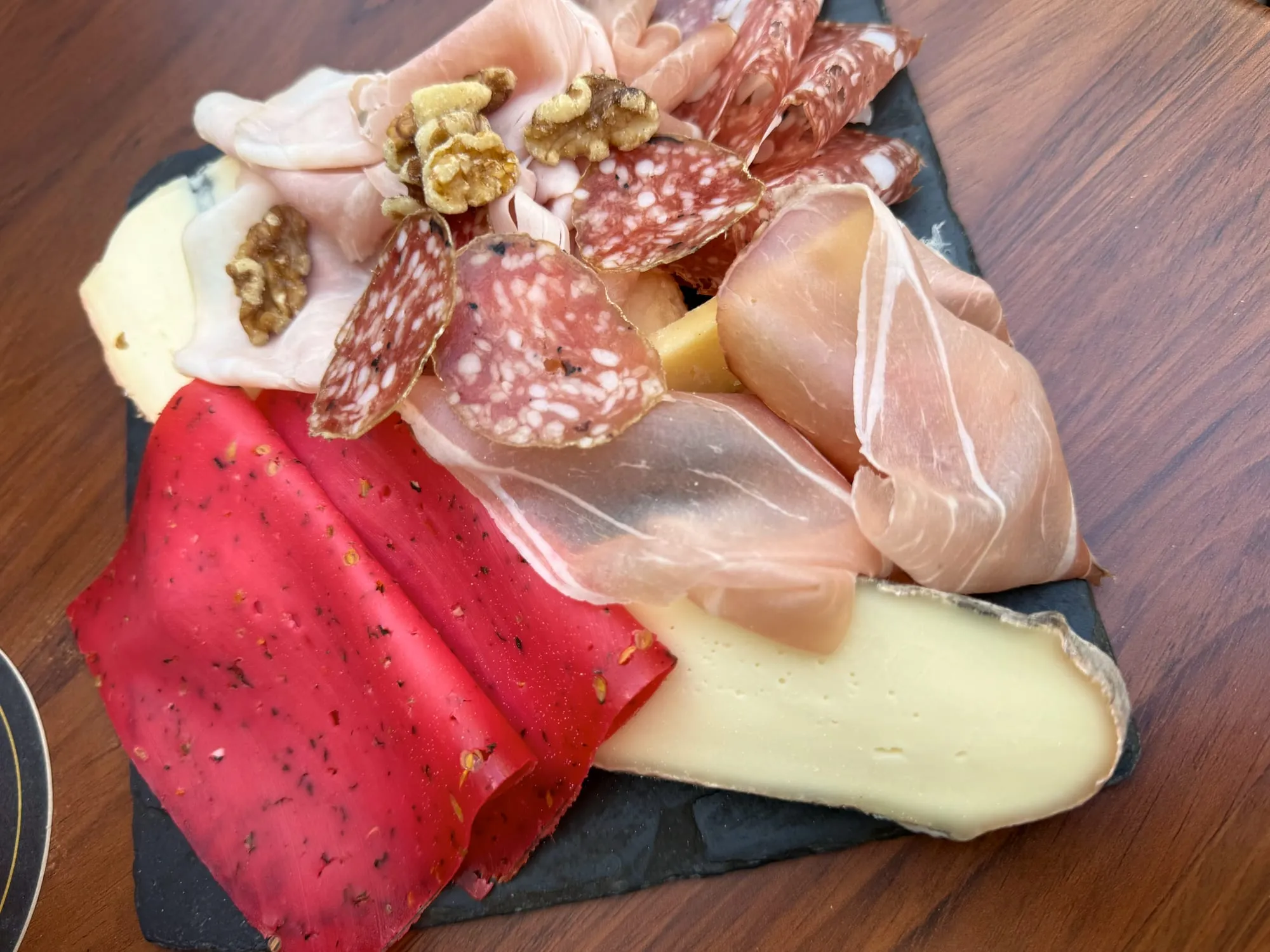 Charcuterie and cheese board with cornichons on a wooden table