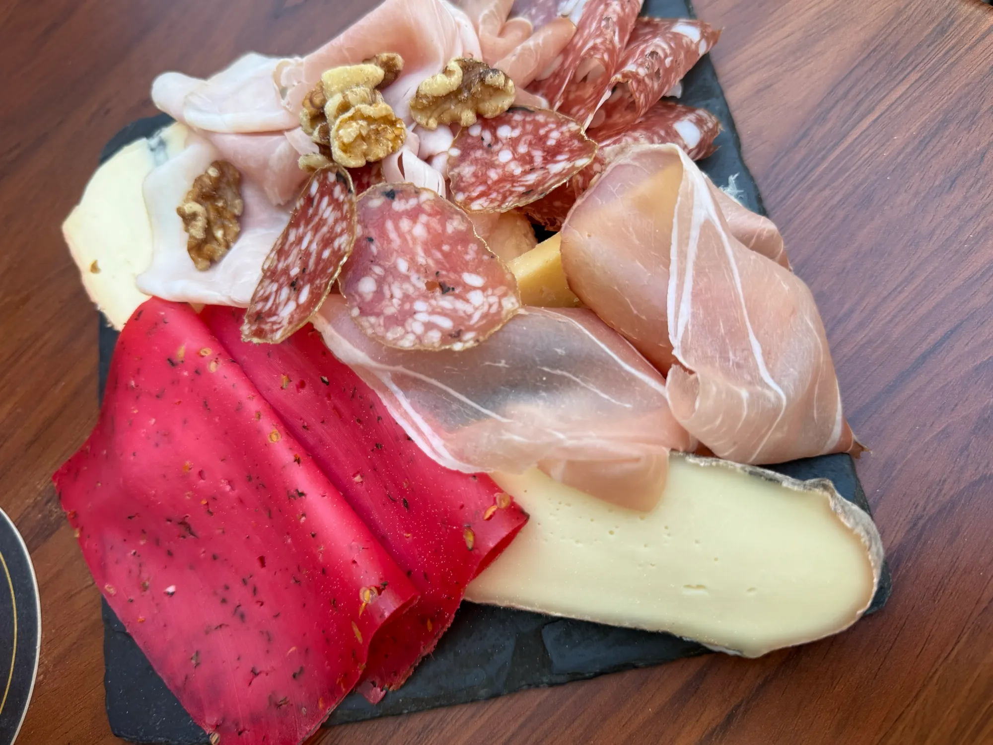 Charcuterie and cheese board with cornichons on a wooden table
