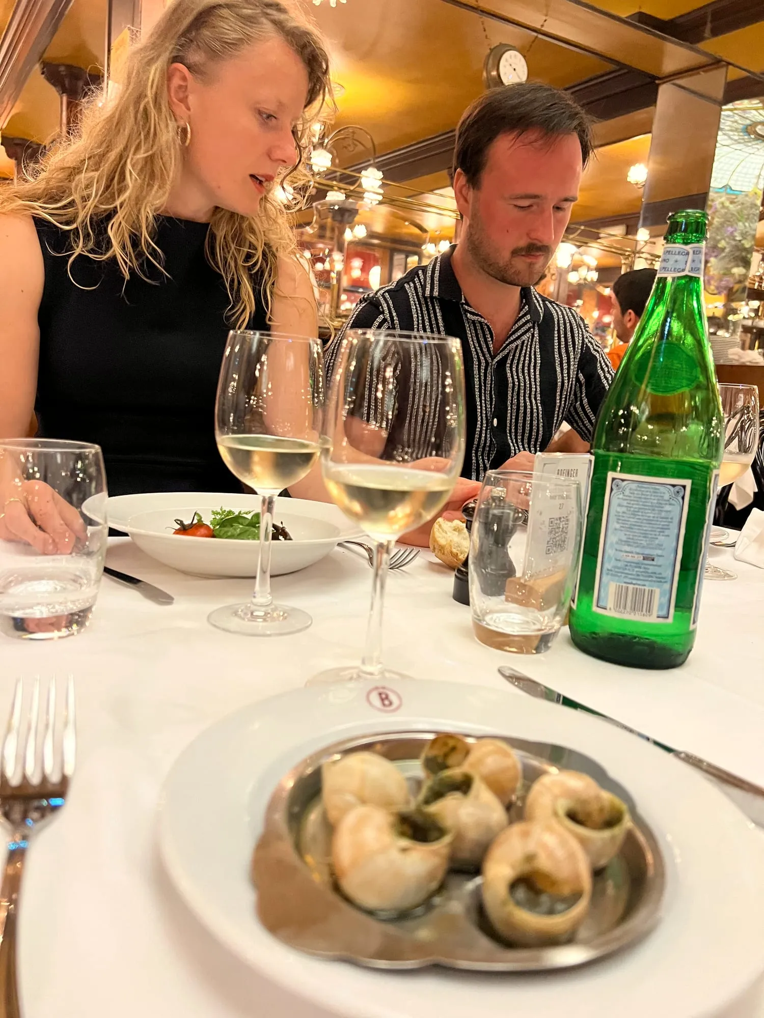 A couple sharing a plate of escargots at a Paris brasserie