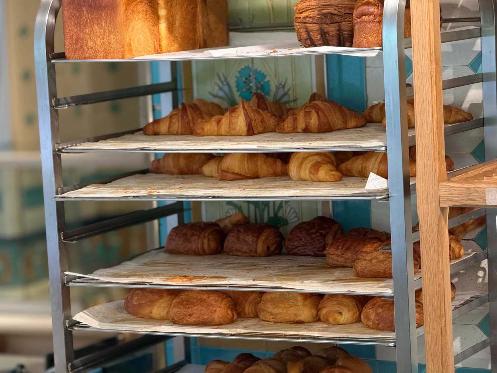 Rack of fresh croissants behind a bakery window