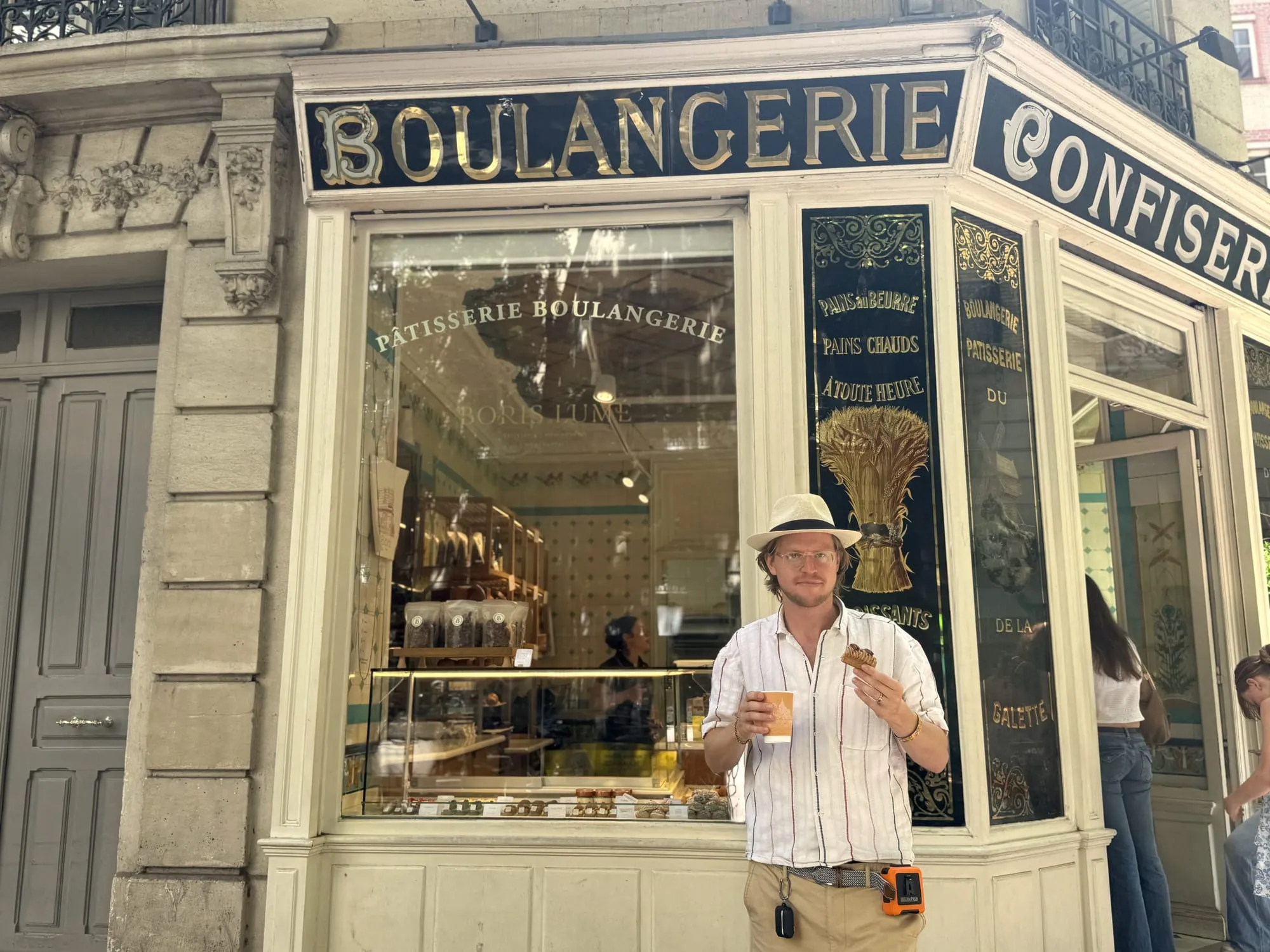 Otto in a panama hat outside a gilded historic boulangerie storefront in Paris
