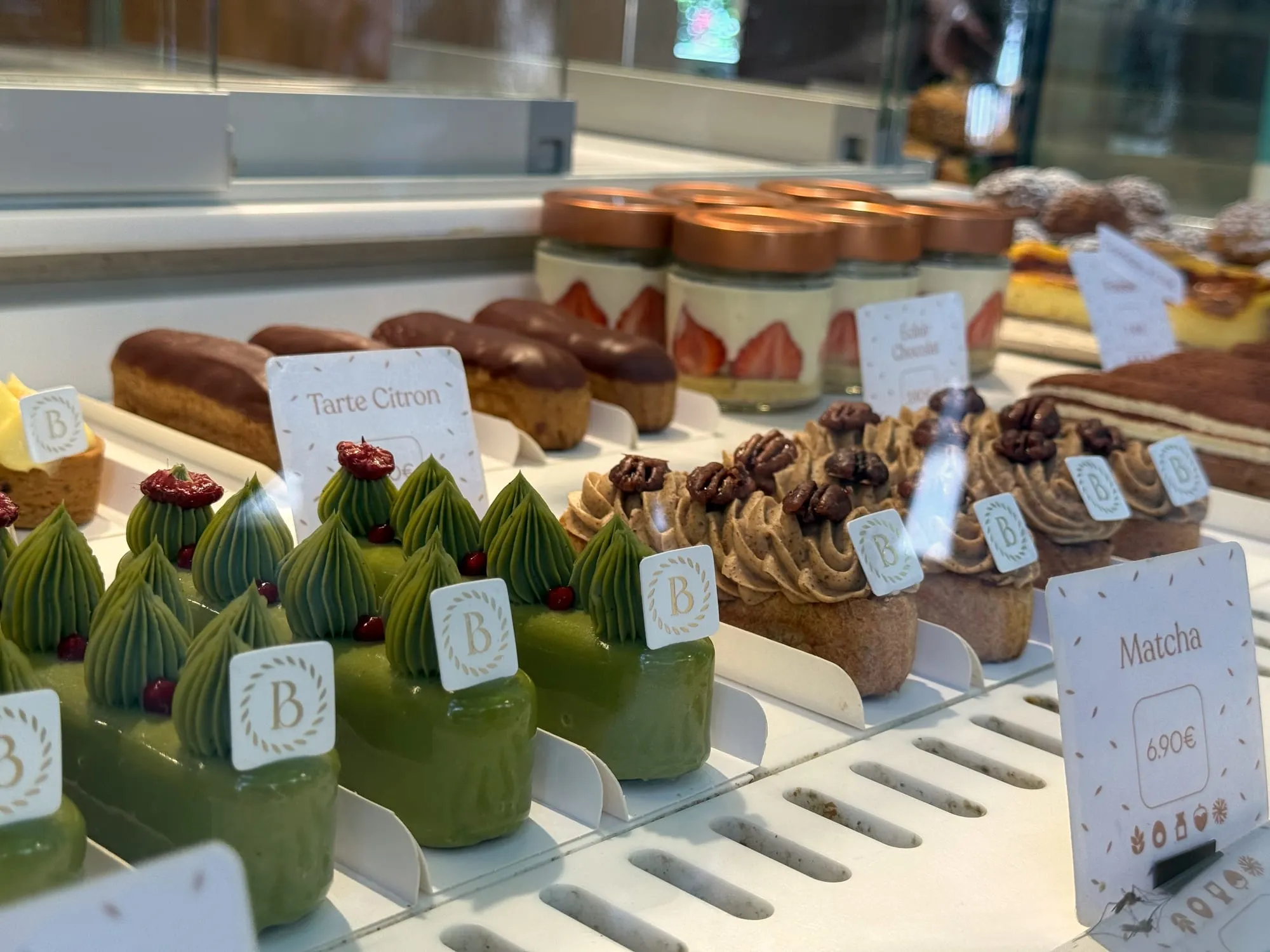 Glass patisserie case with rows of pastries including a matcha tart