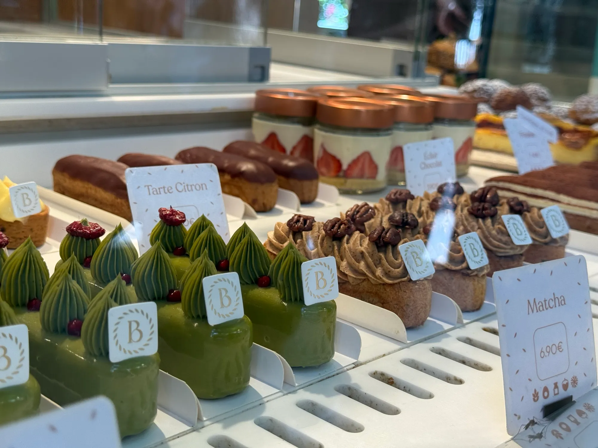 Glass patisserie case with rows of pastries including a matcha tart