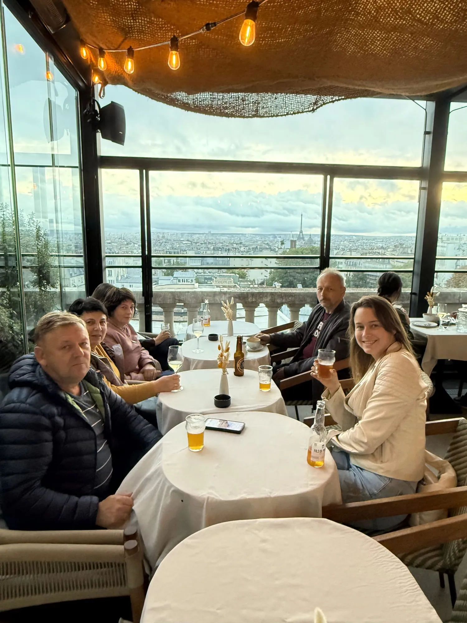 Group of six guests with drinks at a rooftop restaurant overlooking the Paris skyline