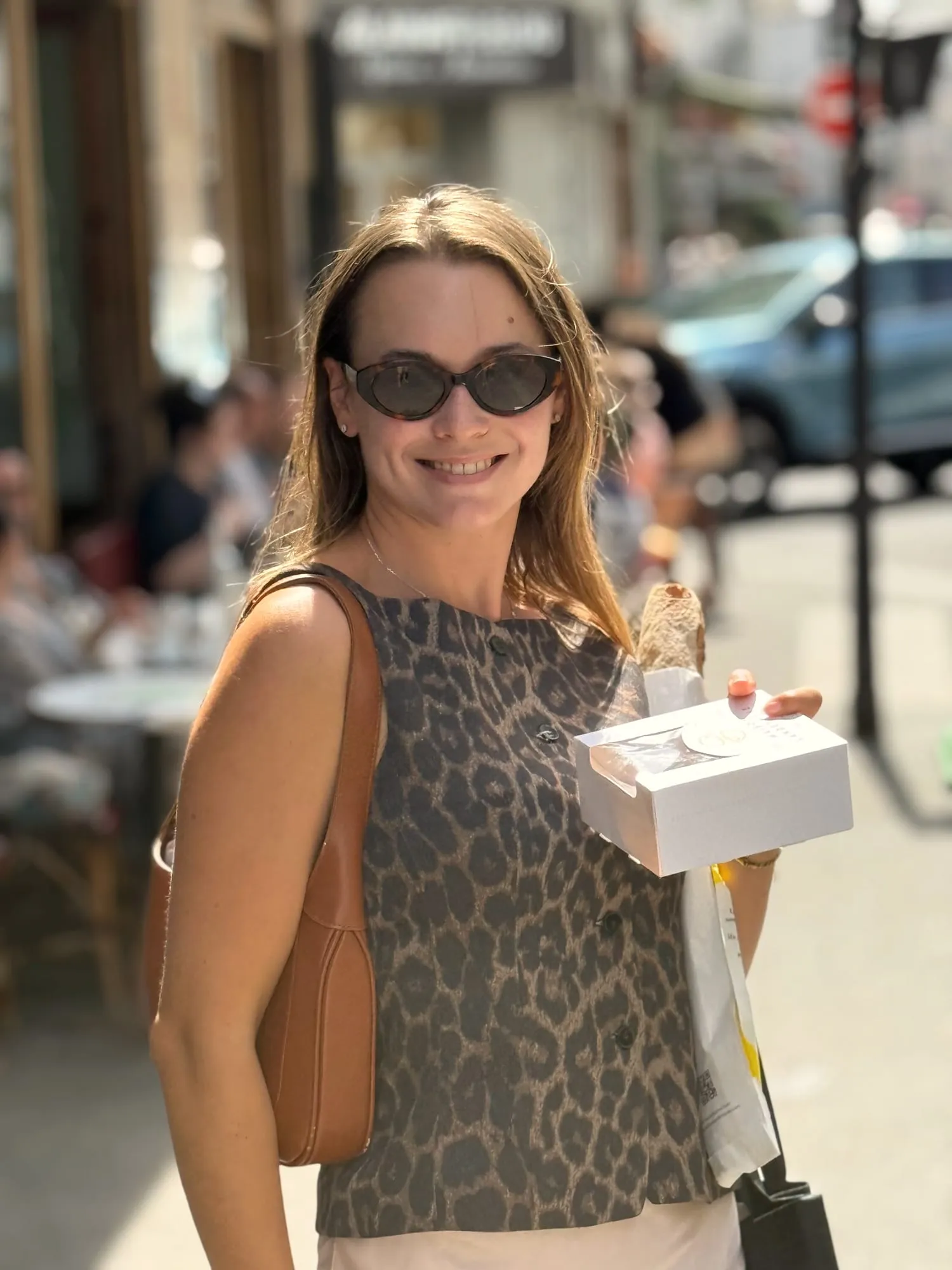 Guest carrying a pastry box and baguette along a Paris street