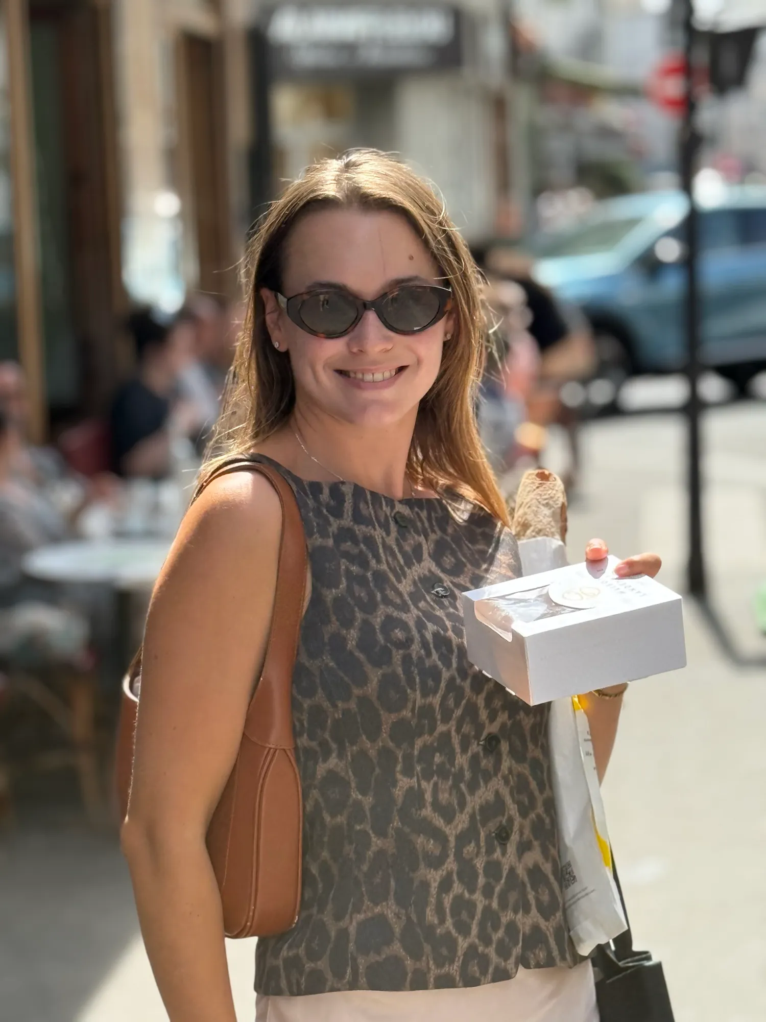 Guest carrying a pastry box and baguette along a Paris street