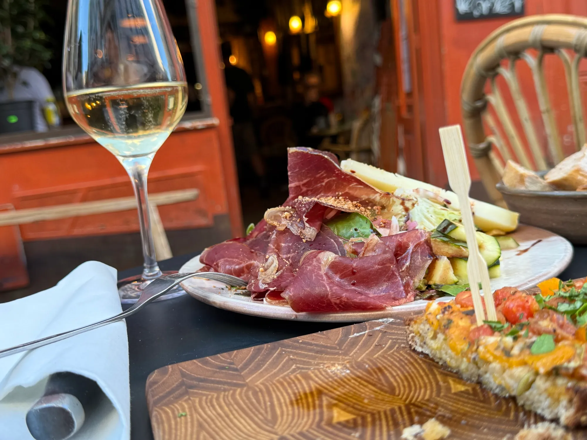Charcuterie plate and a glass of white wine on a bistro terrace table in Paris