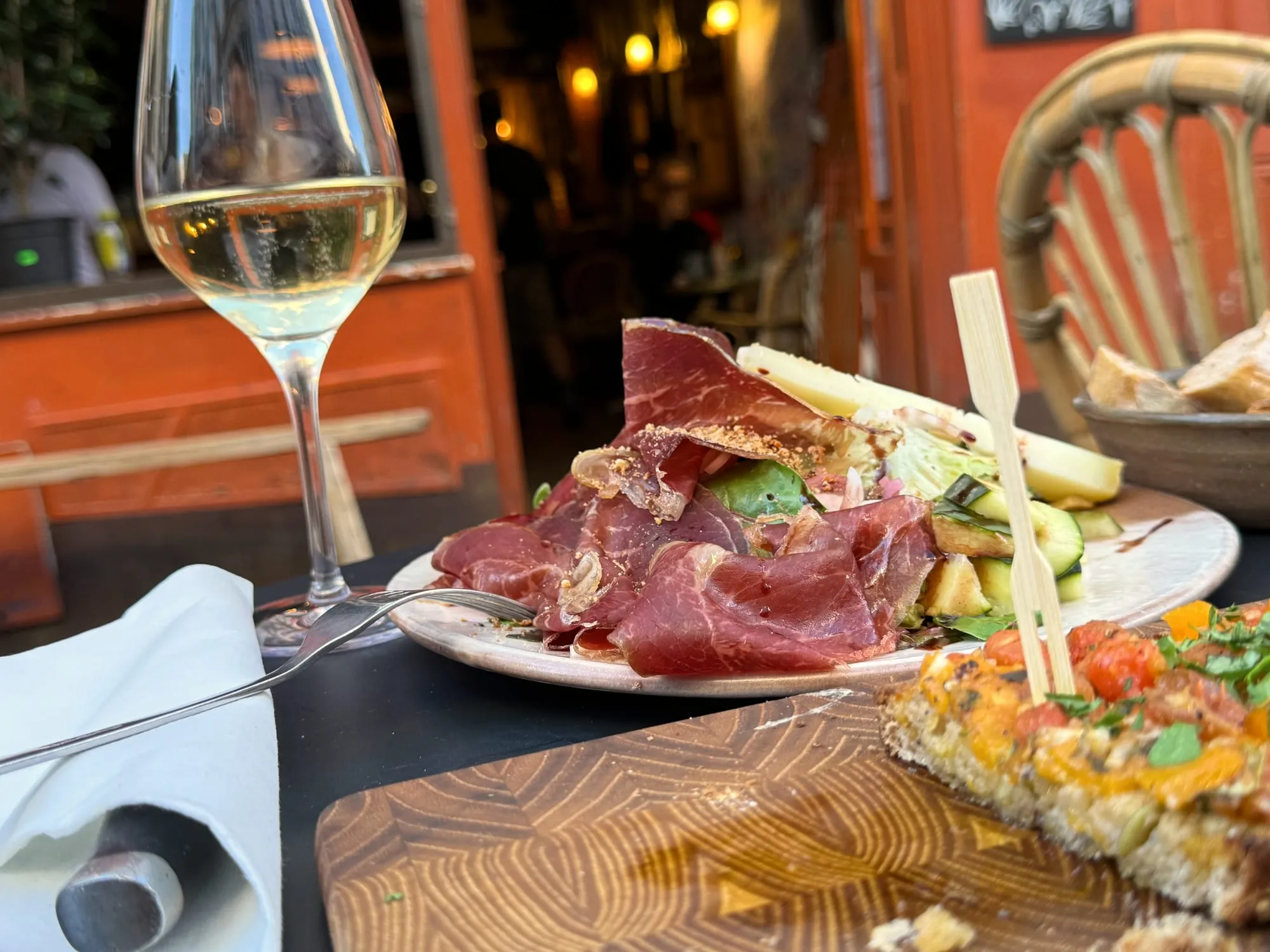 Charcuterie plate and a glass of white wine on a bistro terrace table in Paris