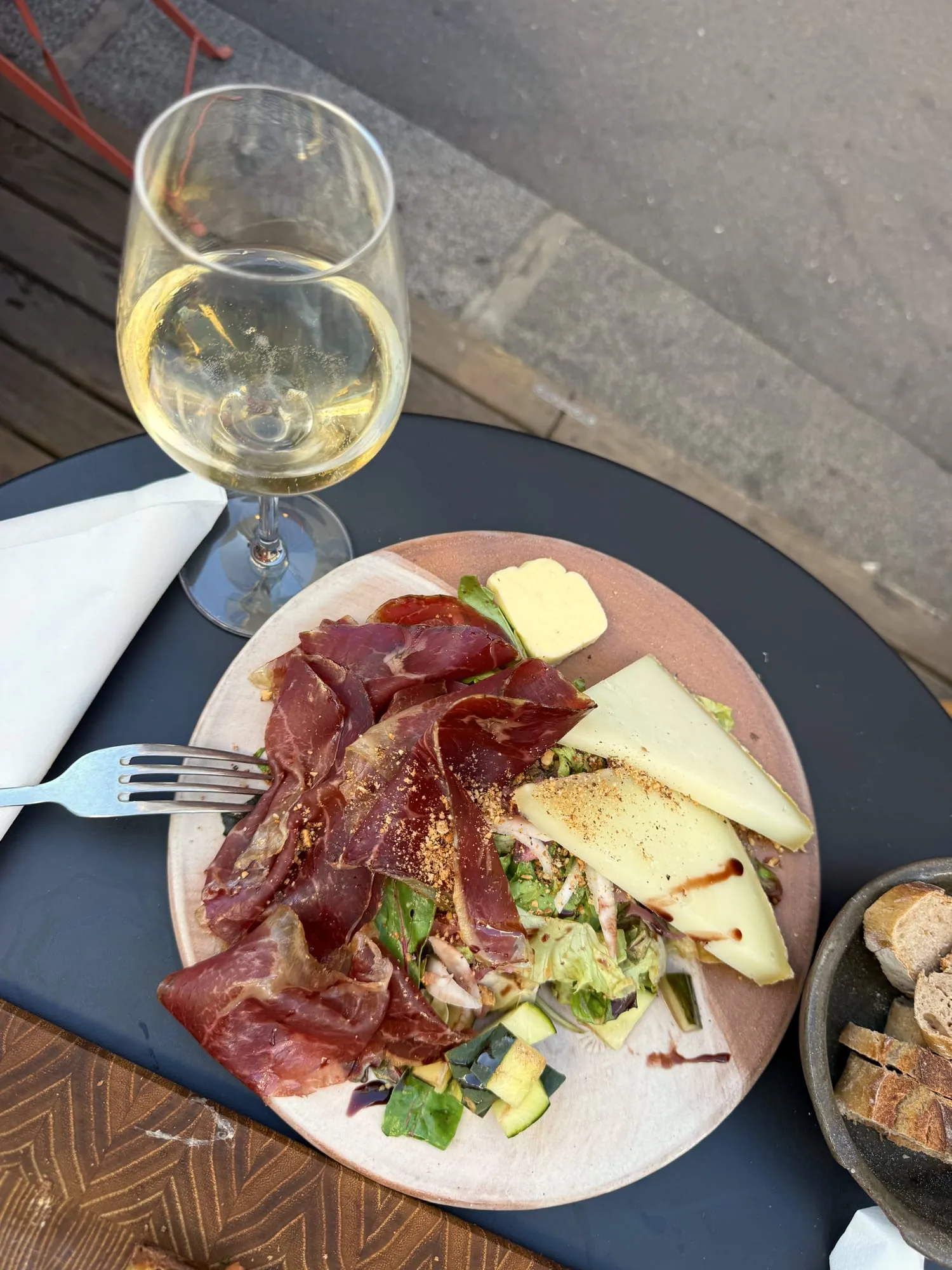 White wine, cured ham and mountain cheese on a Paris terrace table